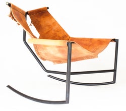 [ee-wah'] chair is a modern rustic rocking chair made from blackened mild steel with brass end plugs and harness leather hand sewn with sinew cord